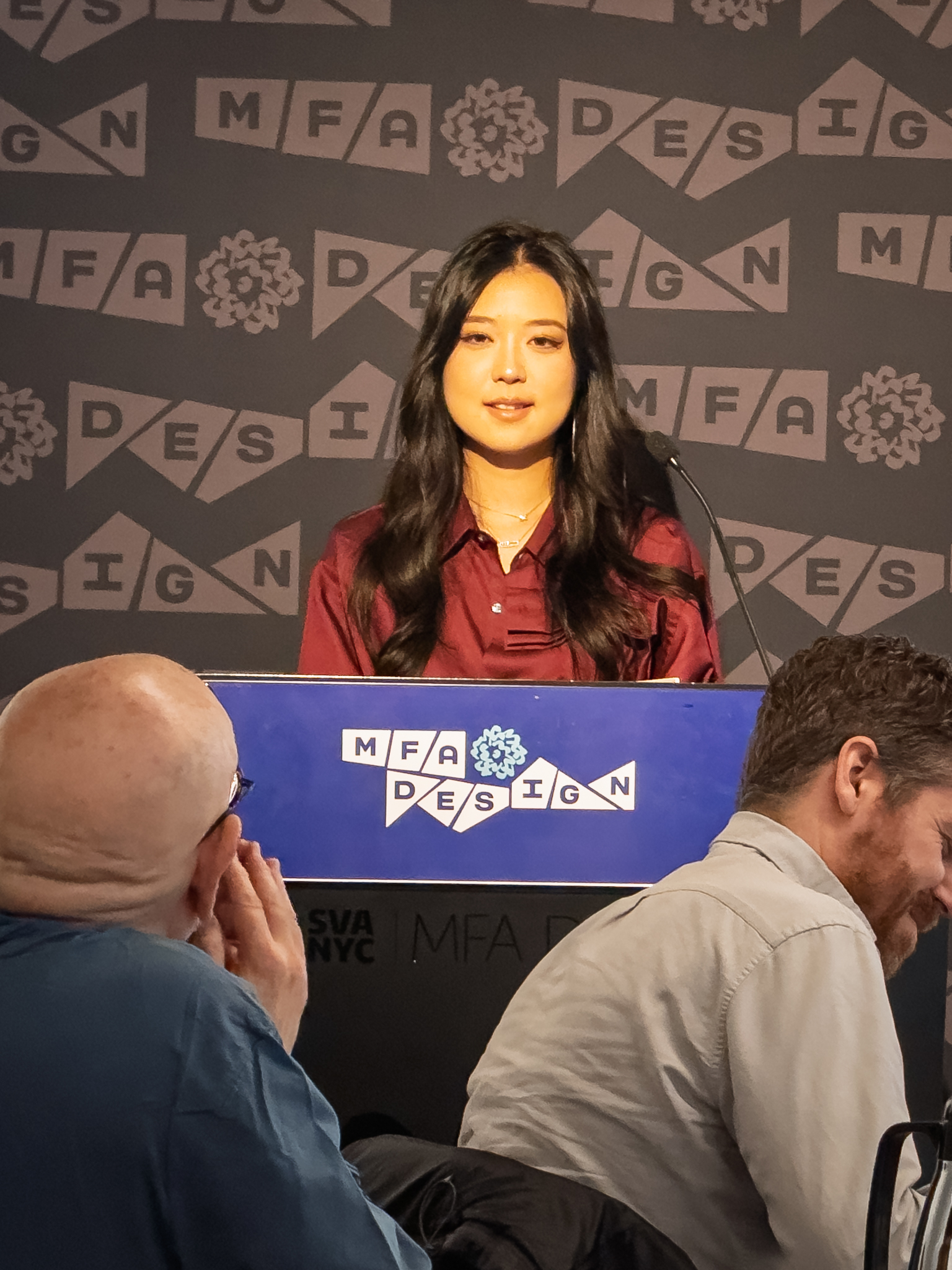 Woman at a podium with microphone, delivering a slide presentation