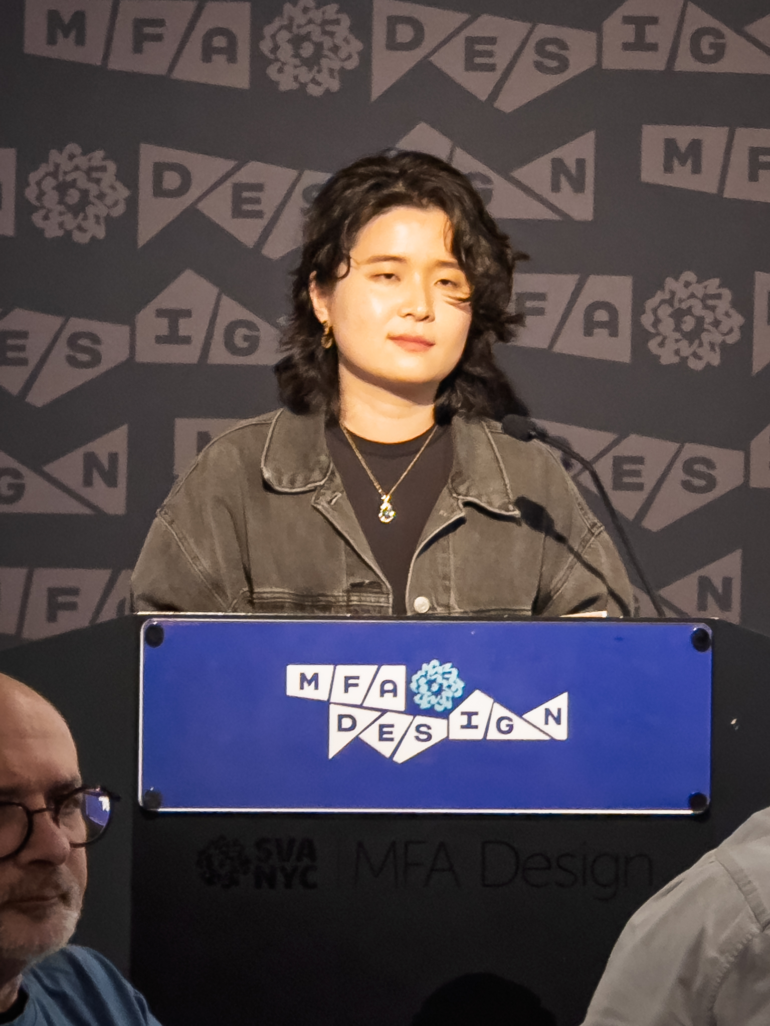 Woman at a podium with microphone, delivering a slide presentation
