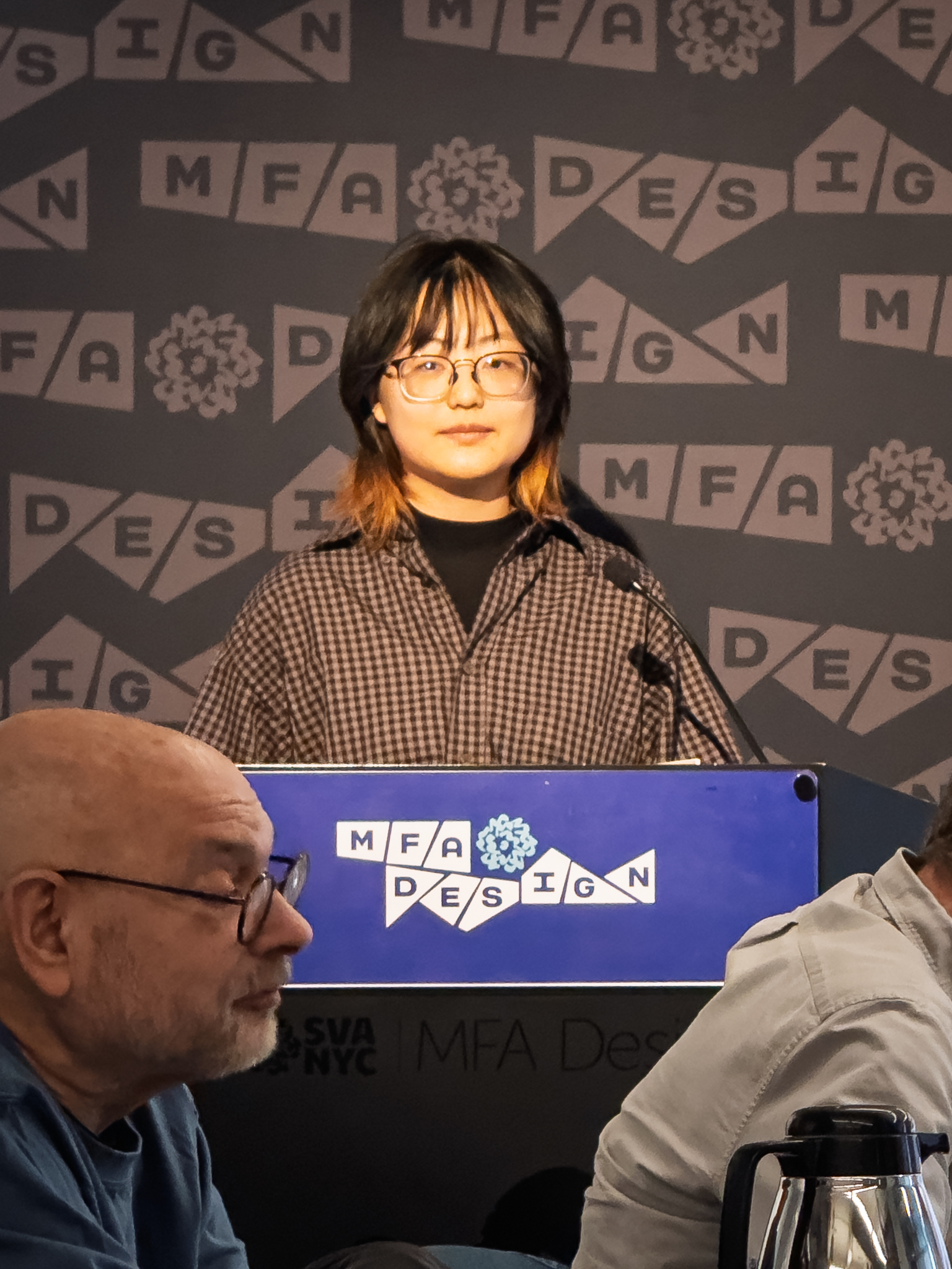 Woman at a podium with microphone, delivering a slide presentation