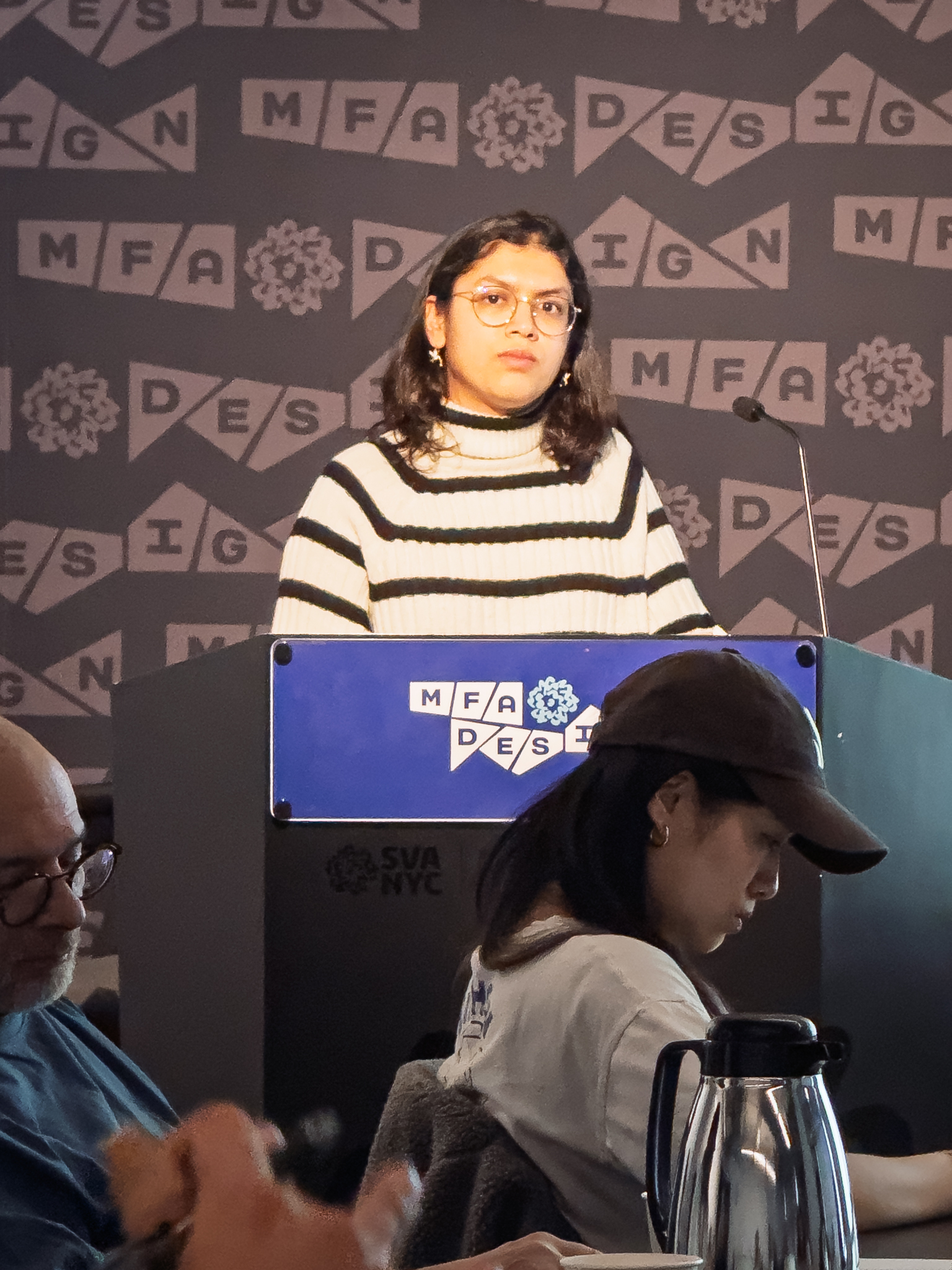 Woman at a podium with microphone, delivering a slide presentation