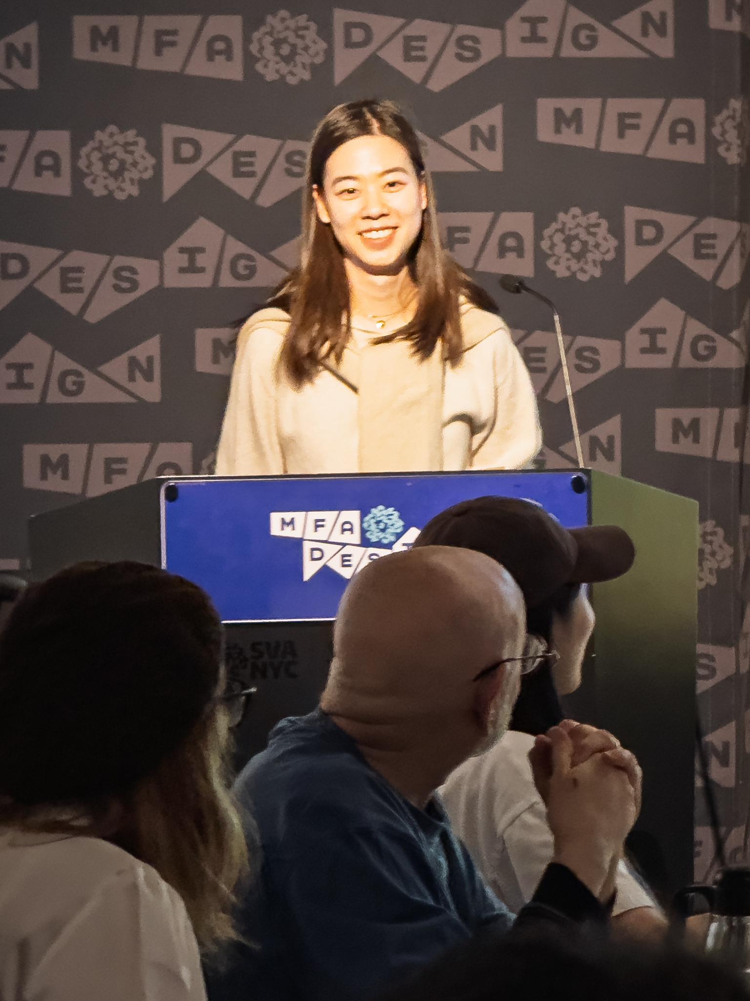 Woman at a podium with microphone, delivering a slide presentation