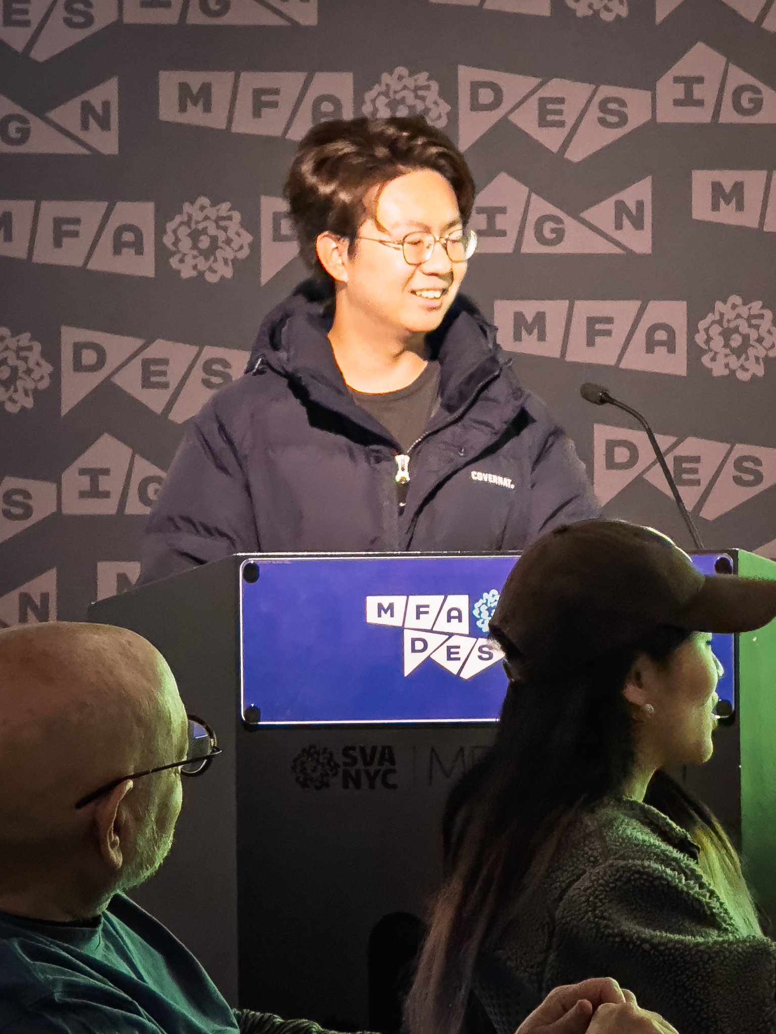 Woman at a podium with microphone, delivering a slide presentation