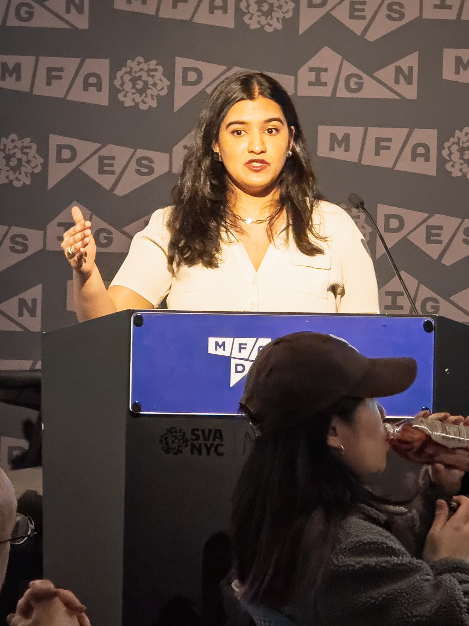 Woman at a podium with microphone, delivering a slide presentation