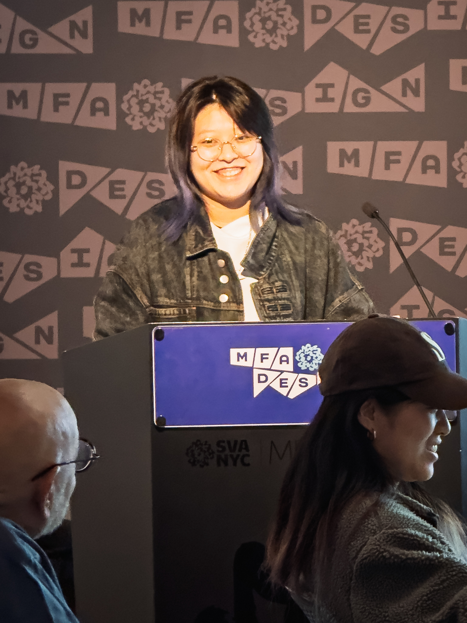 Woman at a podium with microphone, delivering a slide presentation