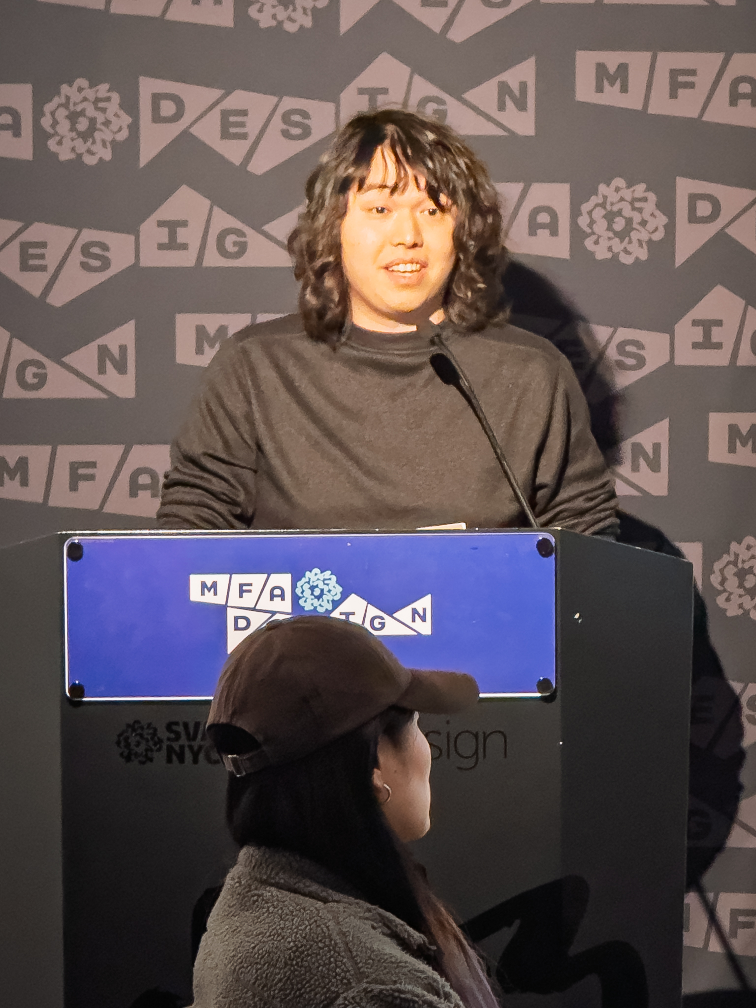 Man at a podium with microphone, delivering a slide presentation