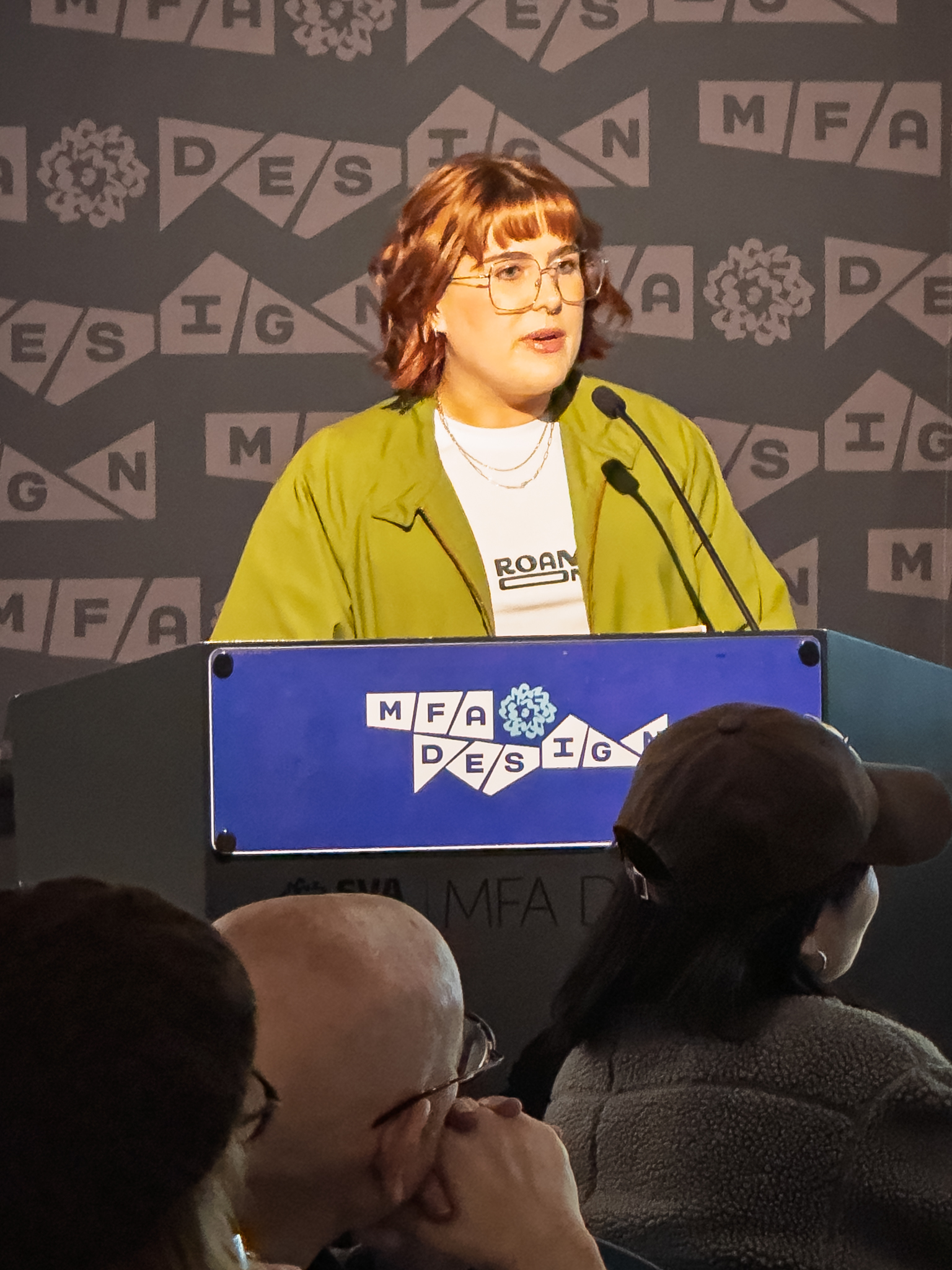 Woman at a podium with microphone, delivering a slide presentation
