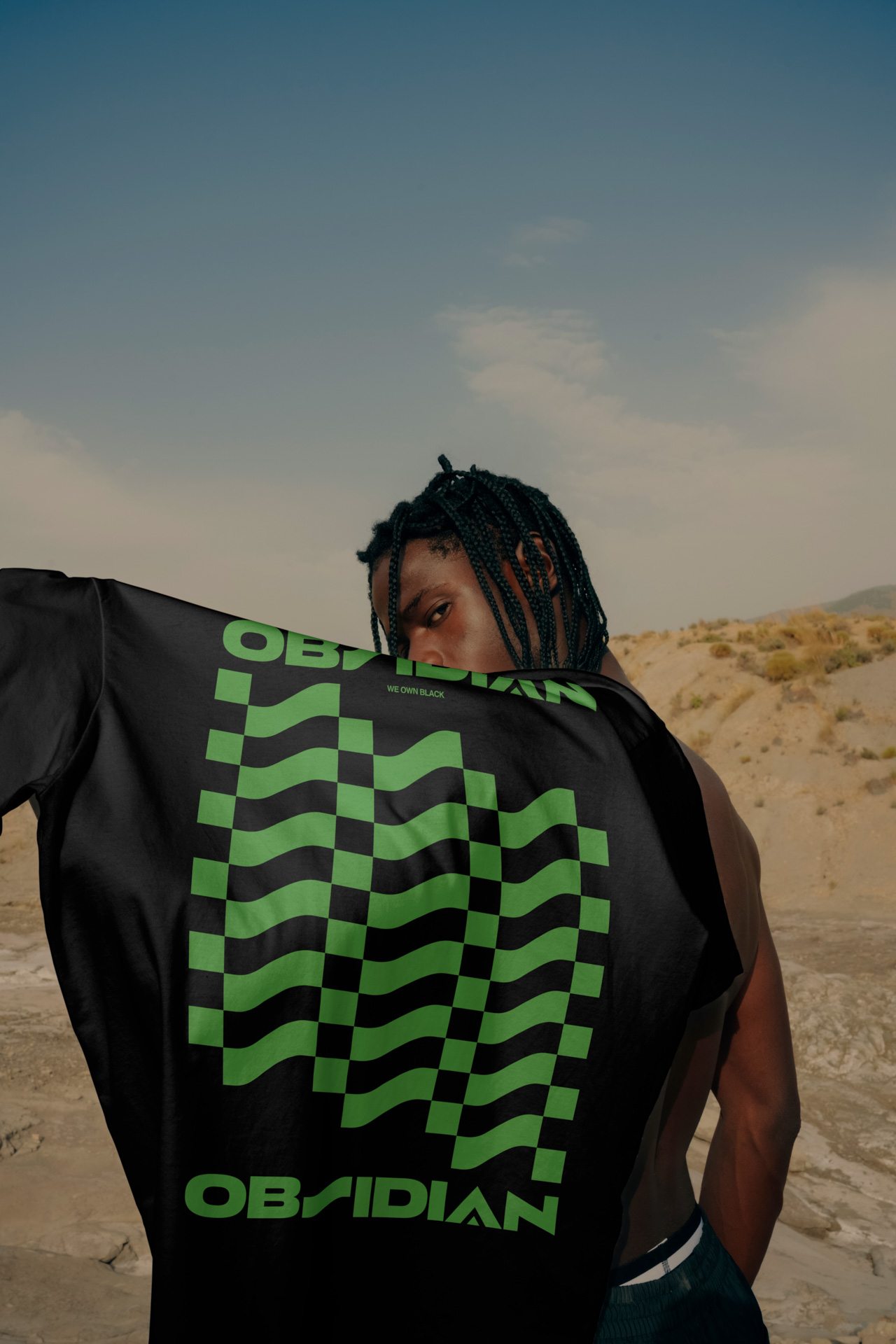 Obsidian  shirt with design on it held by a man, in the desert