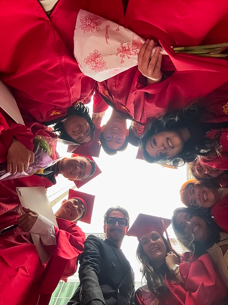 a group of people in commencement gowns looking down at the camera which is pointing up