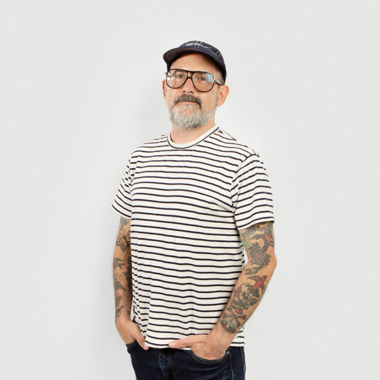 man with glasses and striped shirt, tattoos