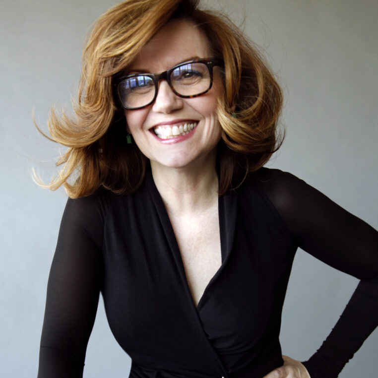 woman smiling wearing black with glasses, shoulder length hair