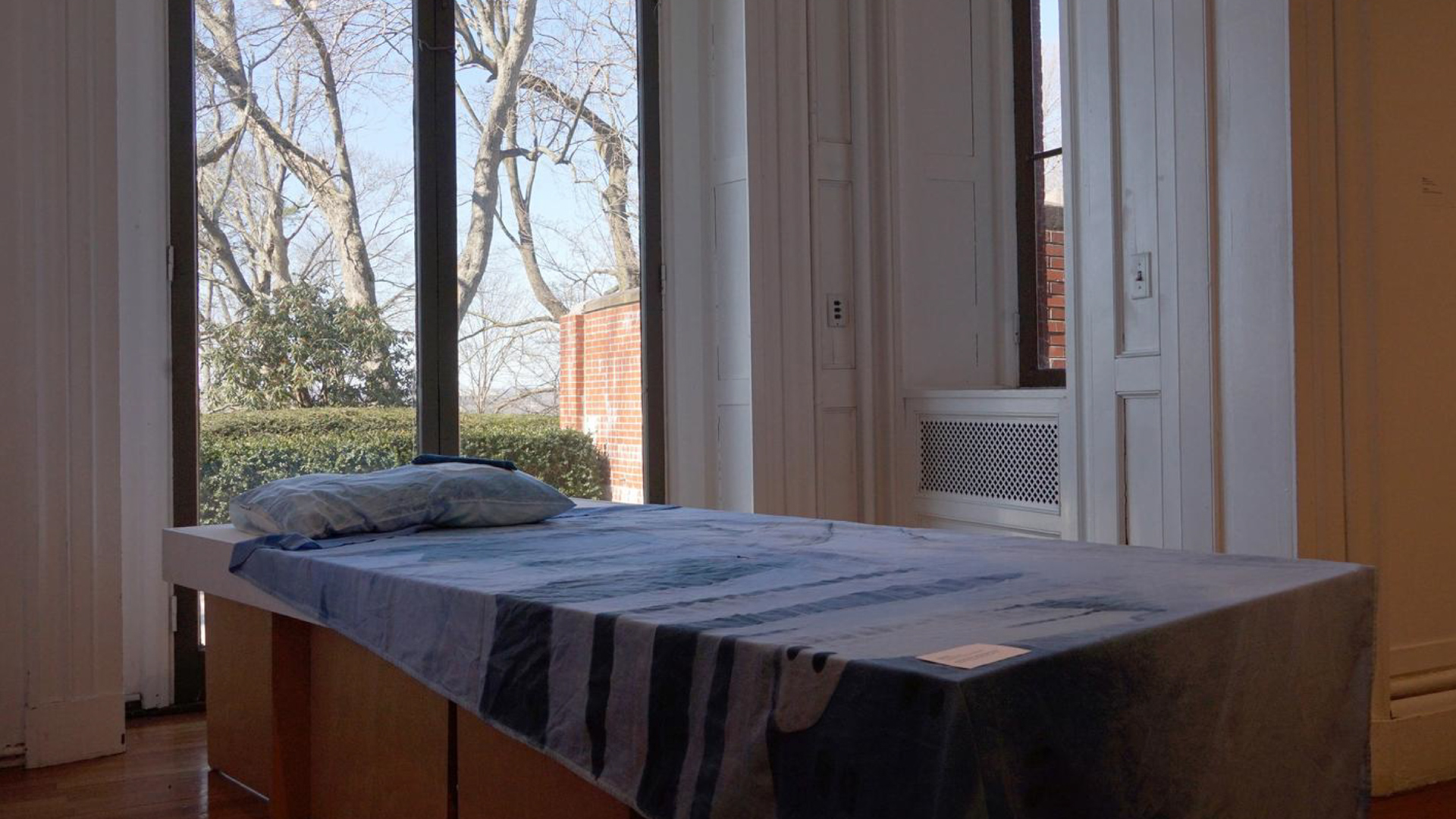 an art installation with a table. on the table is a pillow and a sheet