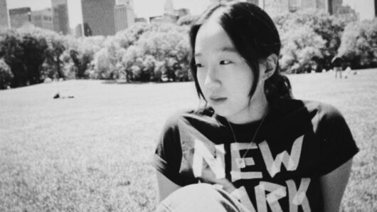 woman looking off camera in a park with a New York City t-shirt
