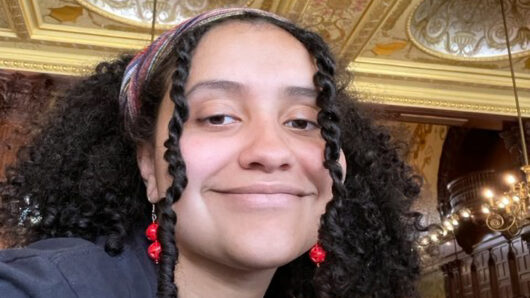 woman with curly hair, smiling, in an ornate room