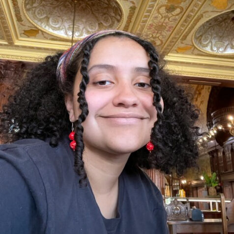 woman with curly hair, smiling, in an ornate room