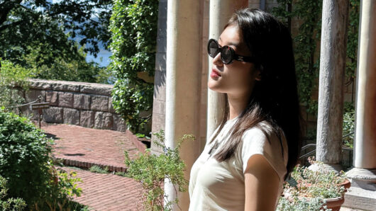 a woman with long hair and sunglasses in a courtyard
