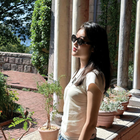 a woman with long hair and sunglasses in a courtyard
