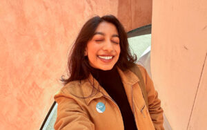 woman with long hair, nose ring and eyes closed smiles at the camera