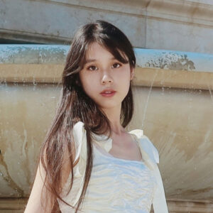 portrait of a woman with long hair in front of a fountain
