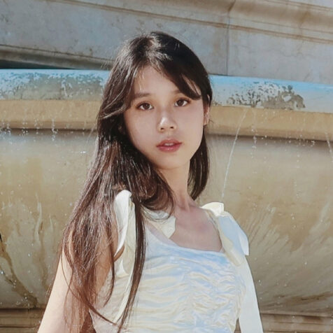 portrait of a woman with long hair in front of a fountain