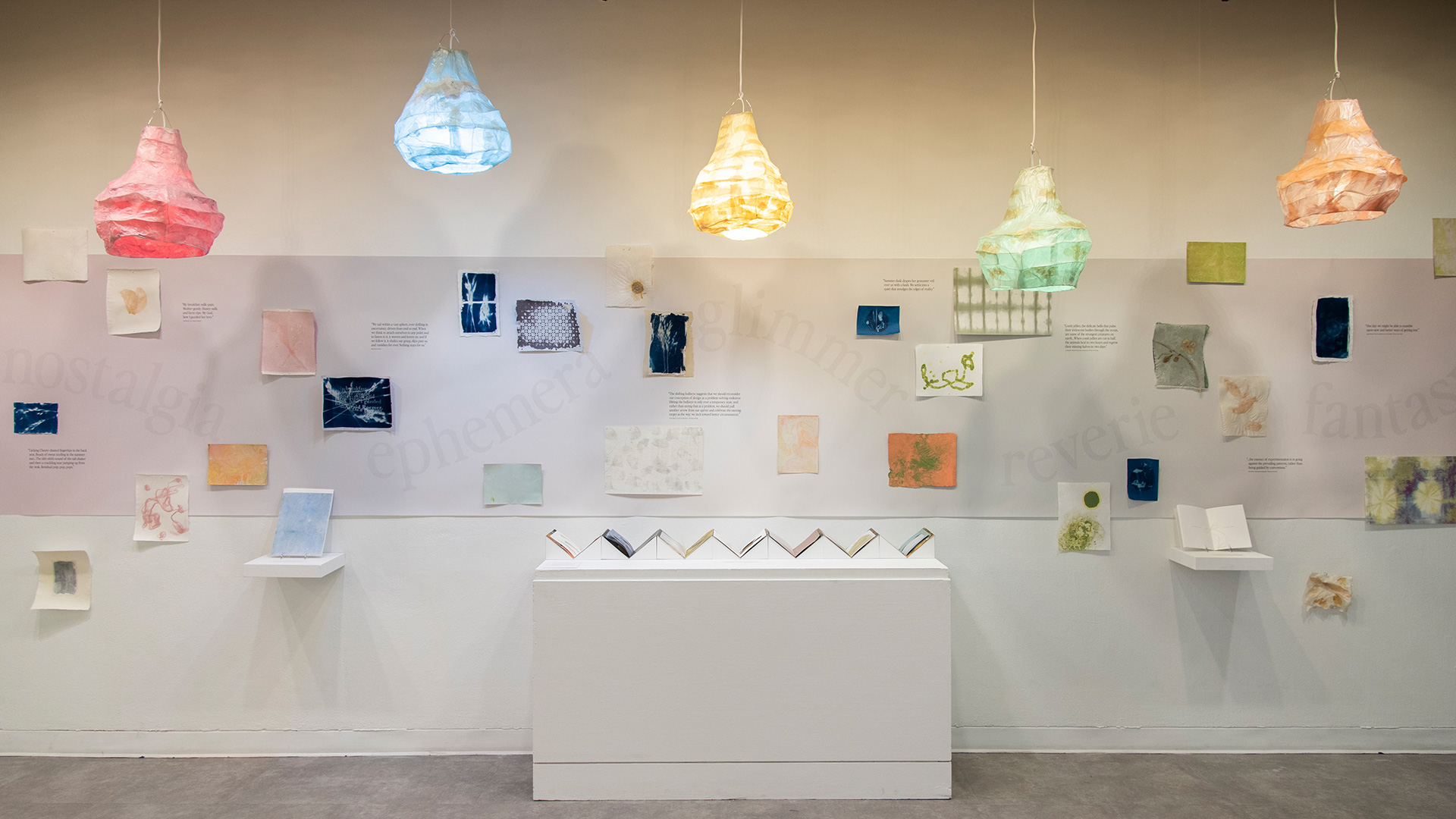 colorful lamps and artwork on the wall of a white gallery