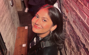 a portrait of a smiling woman in a brick alleyway