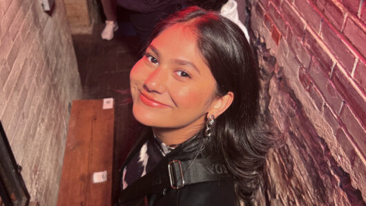 a portrait of a smiling woman in a brick alleyway