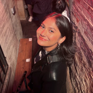 a portrait of a smiling woman in a brick alleyway