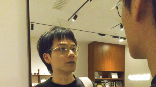 man with glasses looking into a mirror