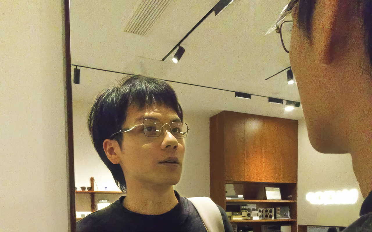 man with glasses looking into a mirror
