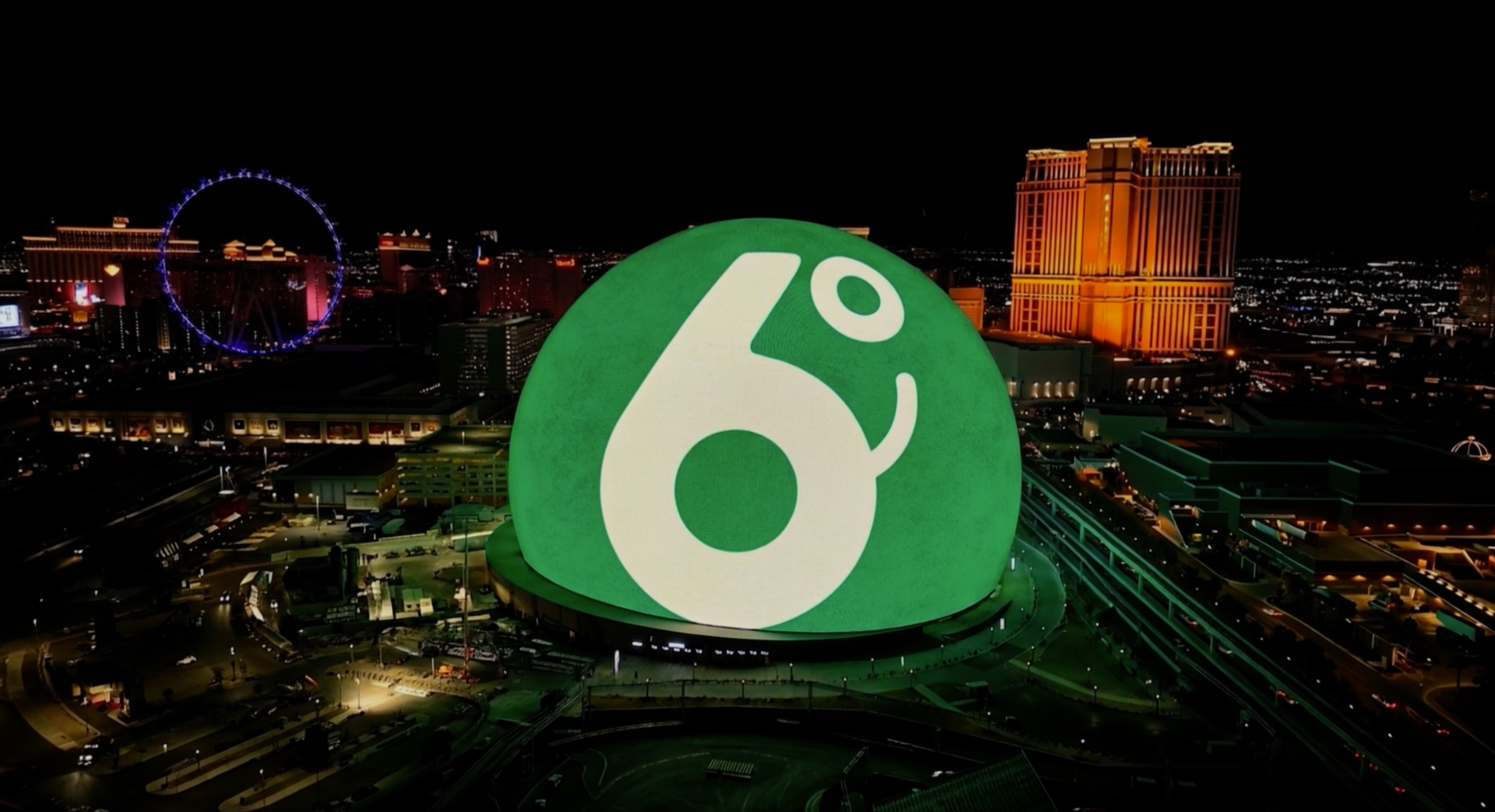 Las Vegas skyline at night featuring the illuminated Sphere displaying the green 6 Degrees logo.