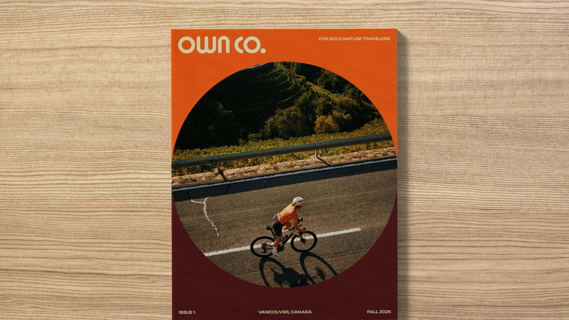 Own Co. magazine cover featuring a cyclist riding along a mountain road with text identifying the issue as “Vancouver, Canada.”