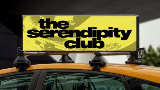 Taxi rooftop advertisement displaying “the serendipity club” in large black text on a yellow background.