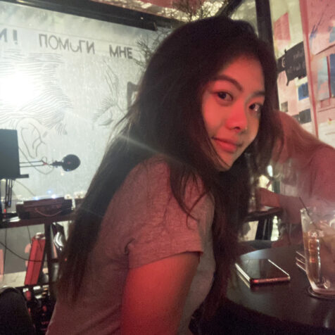 woman with long hair drinking at a bar, red light, window behind