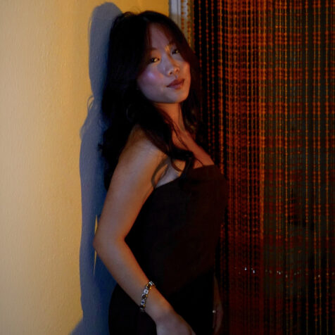 woman with back against a wall looks at camera.