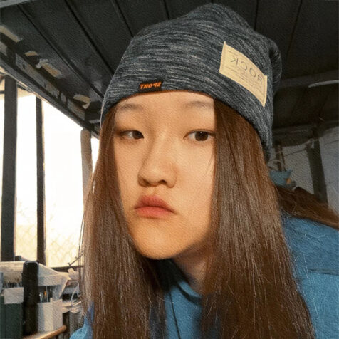 woman with long hair and cap looking at the camera